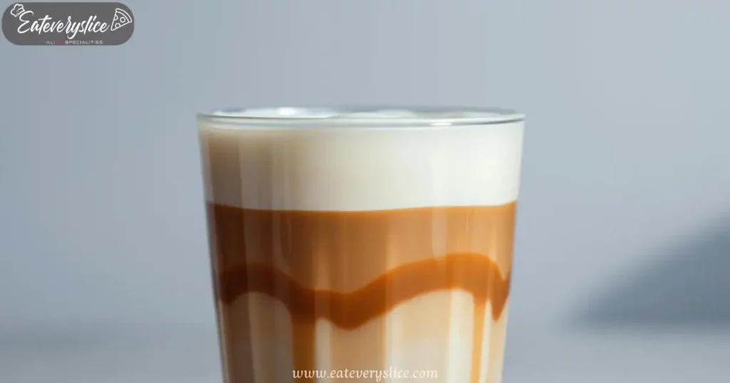 A meticulously layered Latte Macchiato in a clear glass cup, showcasing distinct strata of steamed milk, espresso, and velvety foam, illuminated by soft overhead lighting.